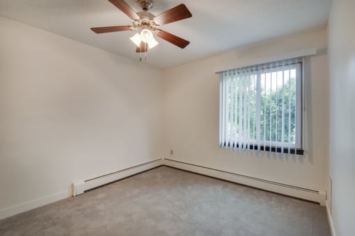 an empty living room with a ceiling fan and a window