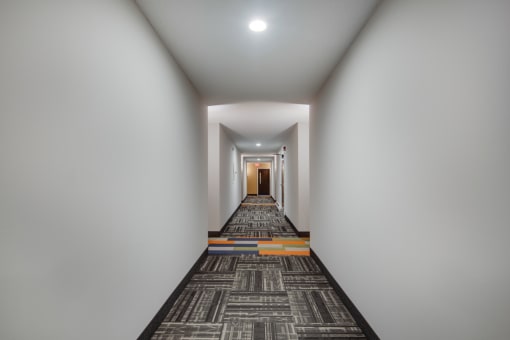 a long corridor with a carpet and white walls and a door