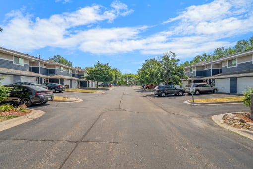 an empty street with houses on either side and cars parked