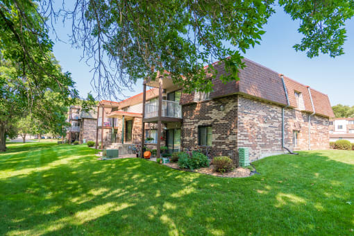 a house with a green lawn and trees in front of it