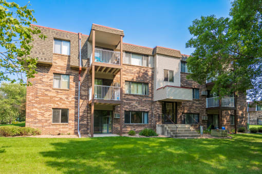a brick apartment building with balconies and a lawn