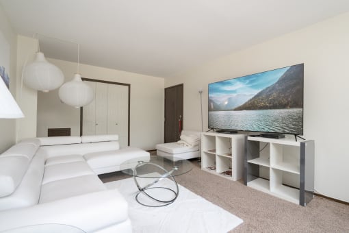 a living room with white furniture and a large screen tv