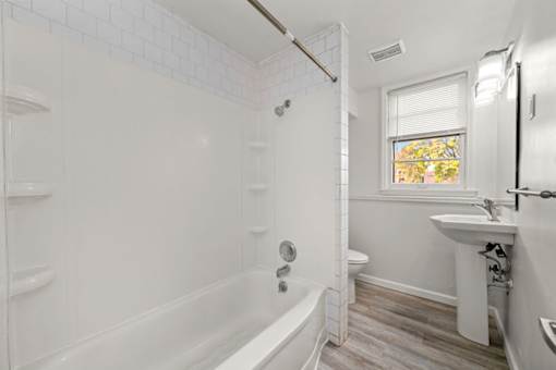 A white bathroom with a tub, sink, and toilet.