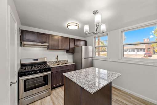 A kitchen with a granite counter top and stainless steel appliances.