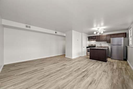 A kitchen area with a refrigerator, sink, and cabinets.
