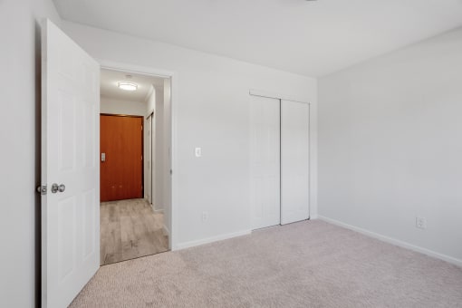 an empty bedroom with white walls and a door to a hallway
