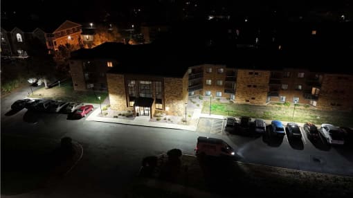 a parking lot at night with cars parked in front of a building