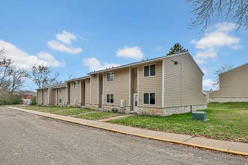 A row of houses with a sidewalk and a tree in the distance.