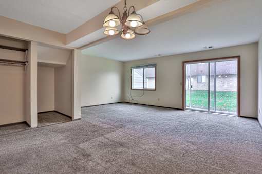 A large, empty room with a carpeted floor and a chandelier hanging from the ceiling.