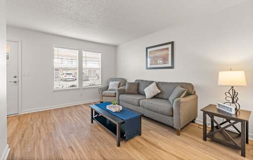 A living room with a grey couch, a blue coffee table, and a lamp.