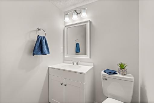 A white bathroom with a towel hanging on the wall.