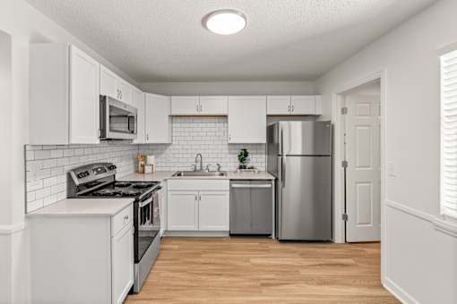 A kitchen with white cabinets and appliances.