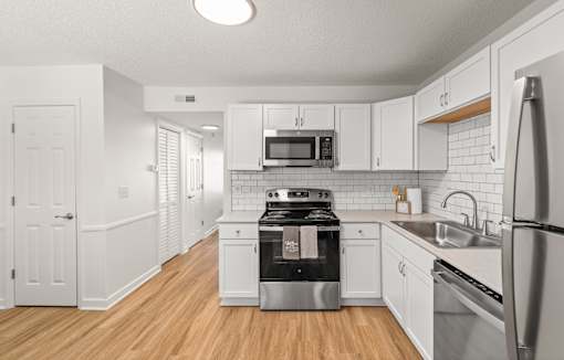 A kitchen with white cabinets and stainless steel appliances.