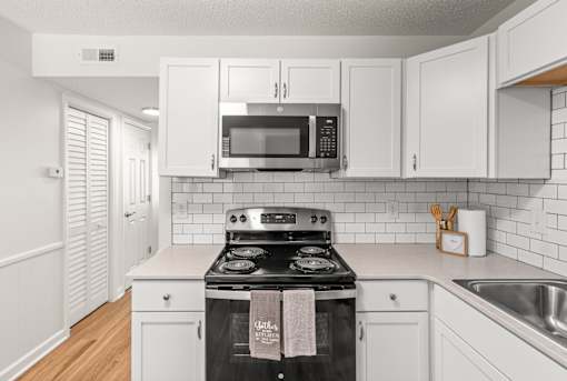 A kitchen with white cabinets and a black stove top.
