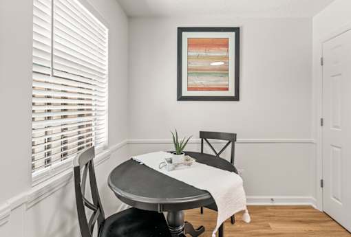 A dining room with a table, chairs and a picture on the wall.