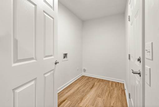 A hallway with white doors and wood flooring.