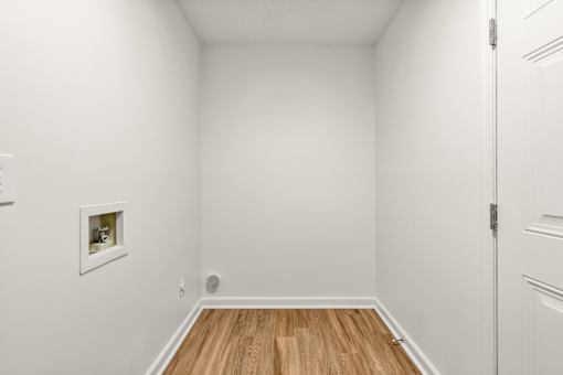 A white room with a wooden floor and a picture on the wall.