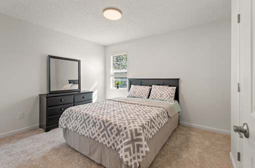 A bedroom with a bed, dresser, and mirror.