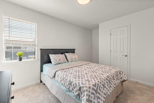 A bedroom with a bed, pillows, and a window.