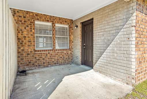 A brick house with a brown door and a concrete driveway.