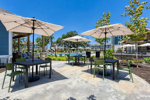 a patio with tables and umbrellas and chairs and a pool at Estraya Boerne, Texas