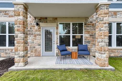 a front porch of a house with two chairs and a table at Estraya Boerne, Texas, 78006