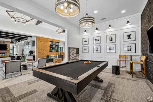 A pool table is in the middle of a room with a chair and a plant.
