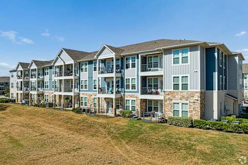 A row of modern apartment buildings with balconies and multiple stories.