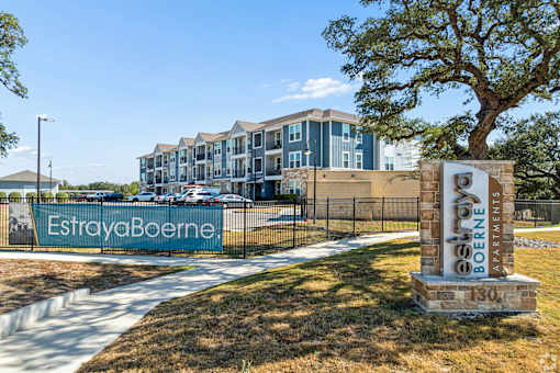 A sign for EstradaBoerne apartments stands in front of a building.