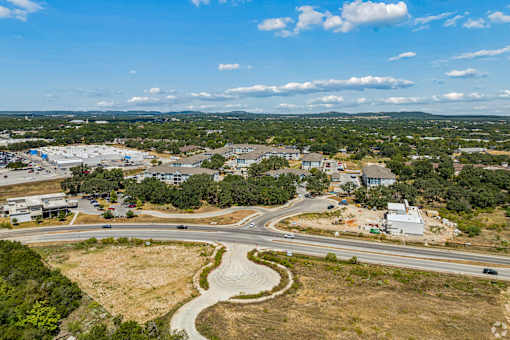 A road with a curve leading to a building with a parking lot in front.