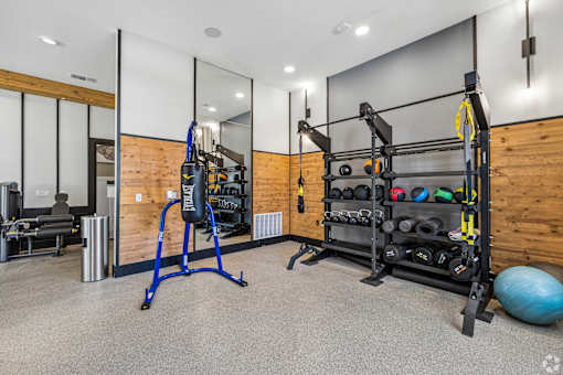 A gym with a blue weight bench, a black weight rack, and a blue exercise ball.