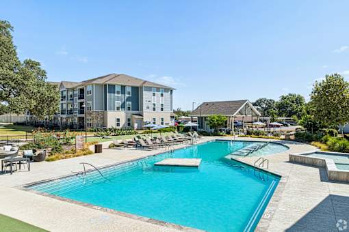 A large swimming pool with a slide in the middle of a grassy area.