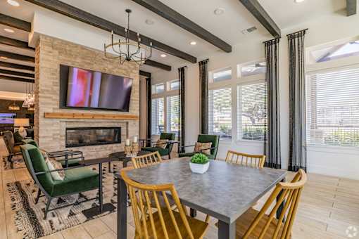A modern dining room with a stone fireplace and a large TV above it.
