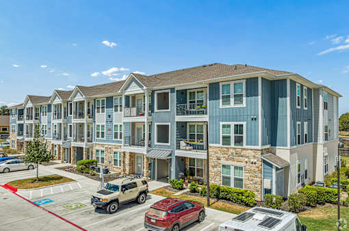A row of townhouses with cars parked in front.