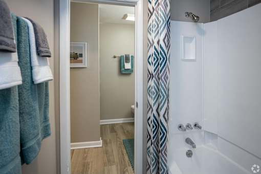 A bathroom with a white tub and a shower with a blue and white curtain.at Addison at Sutherland, Tennessee  