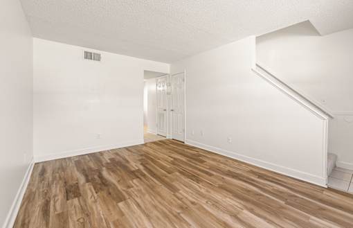 A room with wooden flooring and white walls.