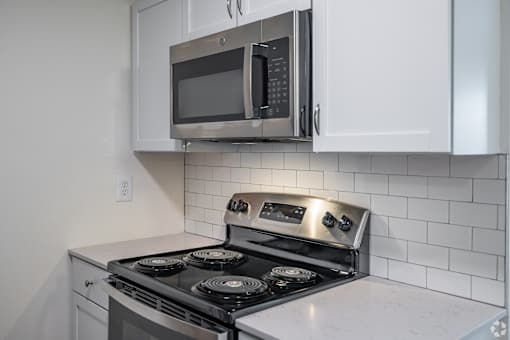 A modern kitchen with a stove top oven and microwave above it.