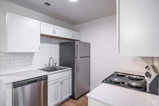 A kitchen with white cabinets and a stainless steel refrigerator.