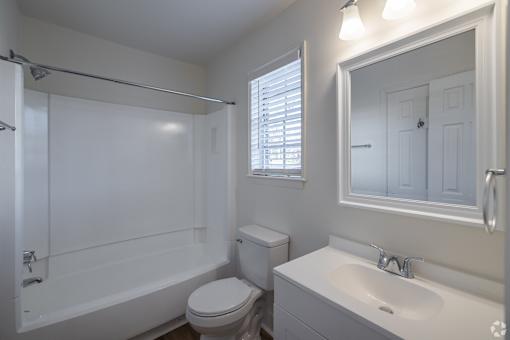 A white bathroom with a toilet, sink, and bathtub.