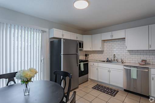 A kitchen with a table and chairs and a vase of flowers.