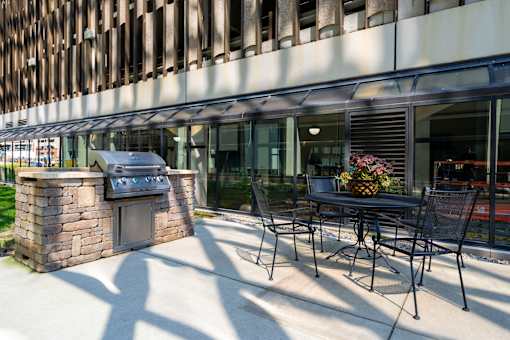 a patio with a table and chairs and a grill outside of a building