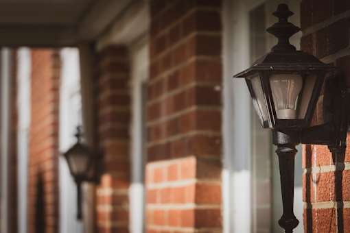 A black street lamp is mounted on a brick wall.