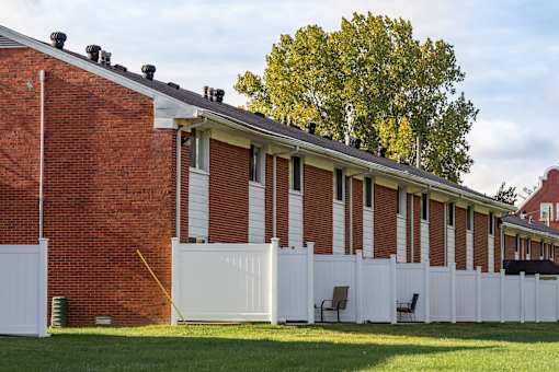 A white picket fence surrounds a red brick building.