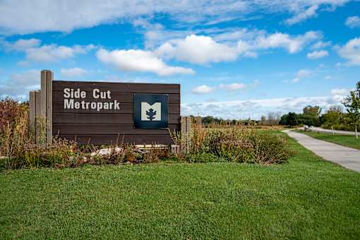 A sign for Side Cut Metropark stands in a grassy field.