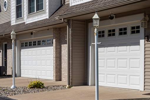 A house with two white garage doors and a lamp post in front.