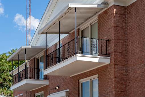 A red brick building with a balcony and a white awning.