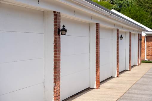 A row of white garage doors with brick pillars.