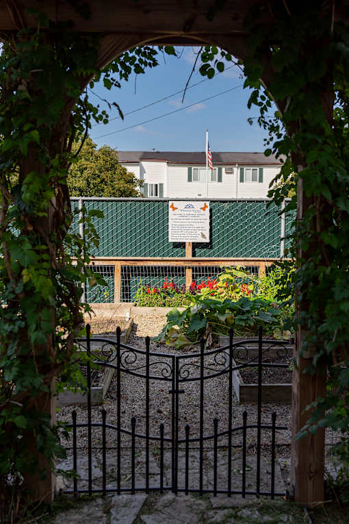 A gate with a sign in front of a building with an American flag.