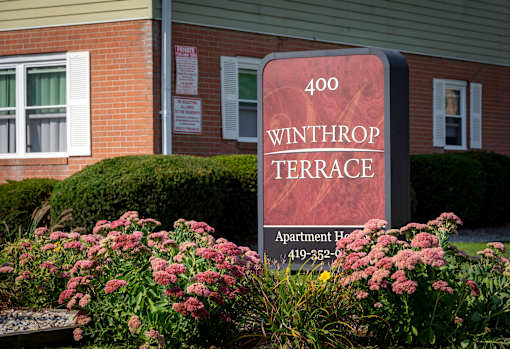 A sign for Winthrop Terrace Apartment Hotel with a phone number on it.