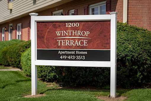 A sign for Winthrop Terrace Apartments is displayed in front of a building.